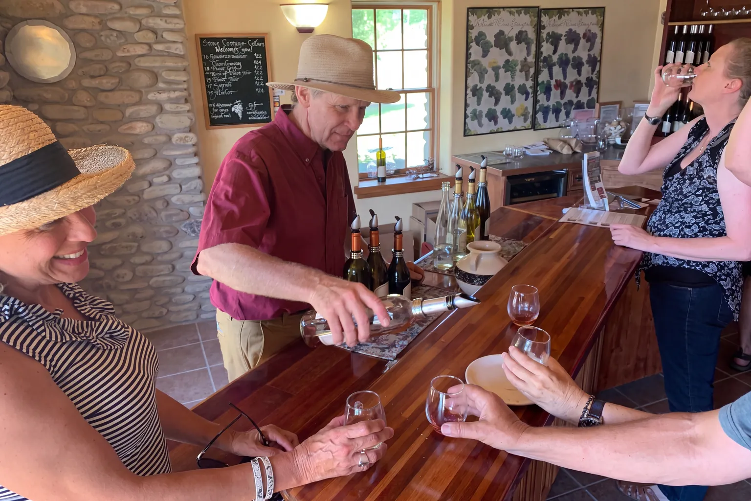 A host pouring wine for guests at the indoor tasting counter at Stone Cottage Cellars