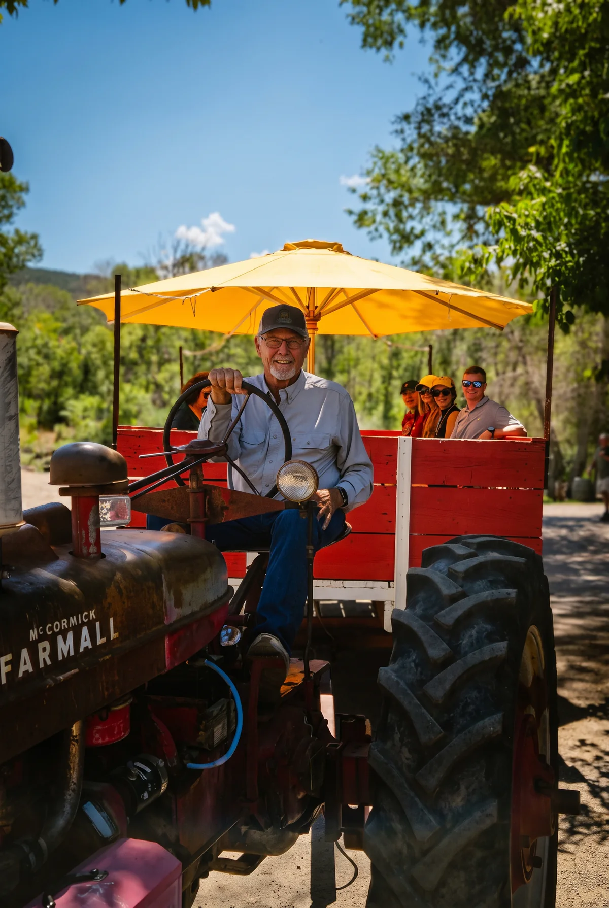 Dave driving a vintage farm tractor with tour guests in Western Colorado