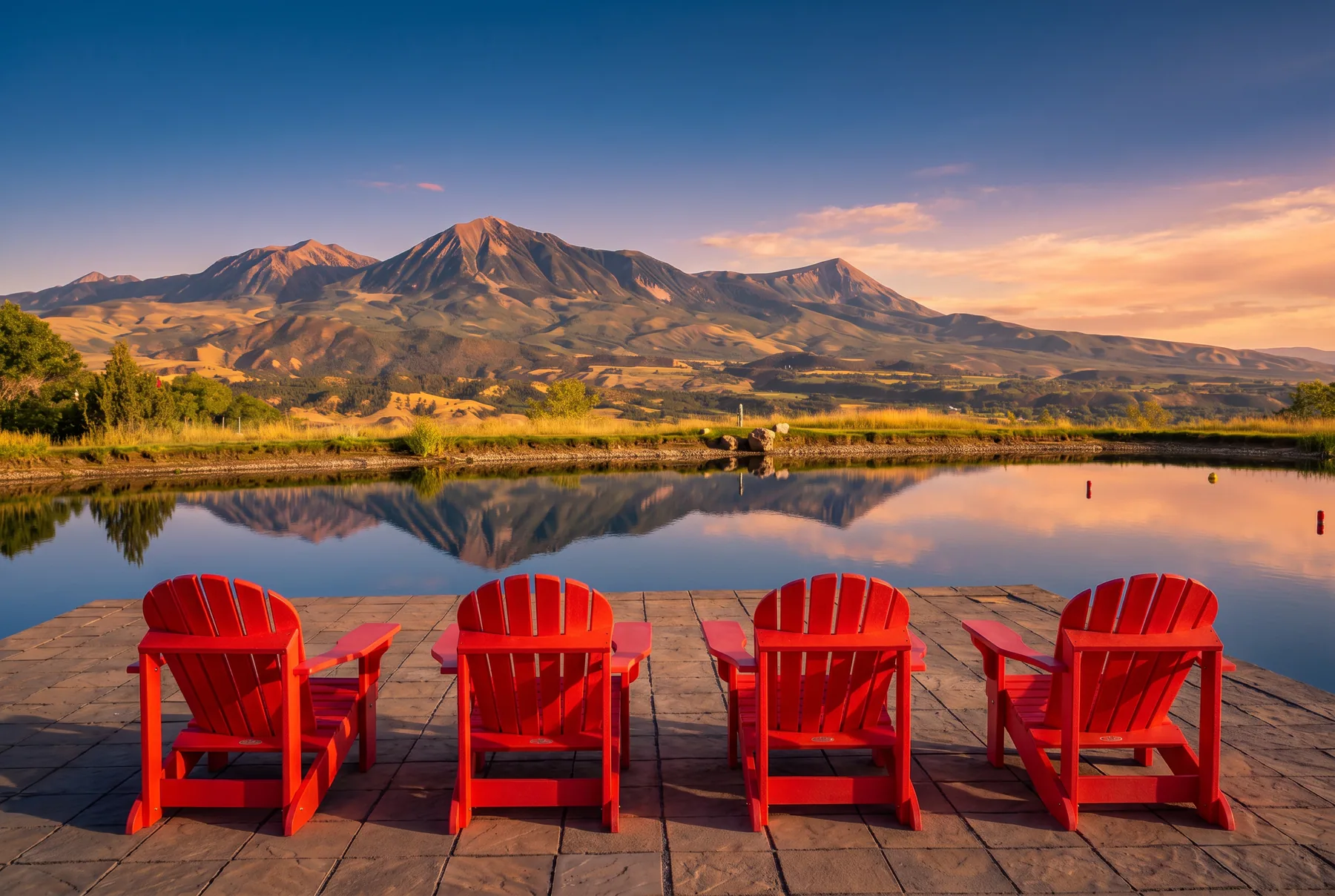 Red chairs beside a lake overlooking a Western Colorado mountain landscape