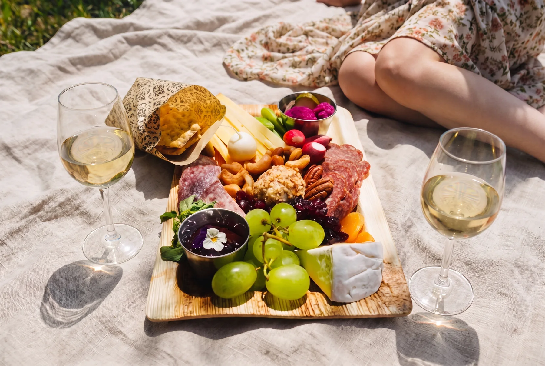 A picnic spread with wine, cheese, fruit, bread, and charcuterie